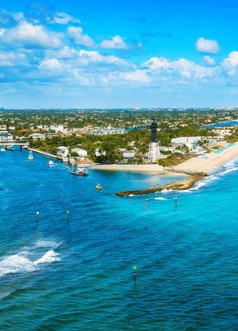 Aerial view of the coast, with vegetation, buildings and clear sky in the background