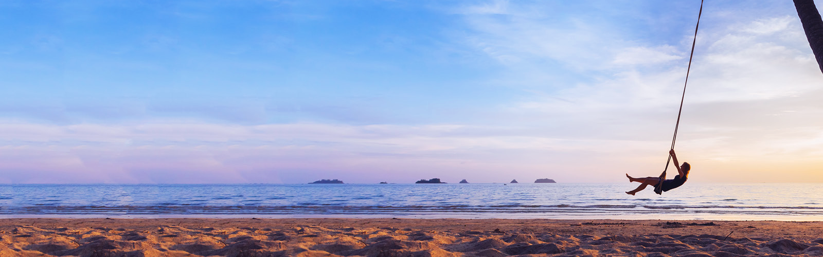 A person swinging on a sunset beach front swing