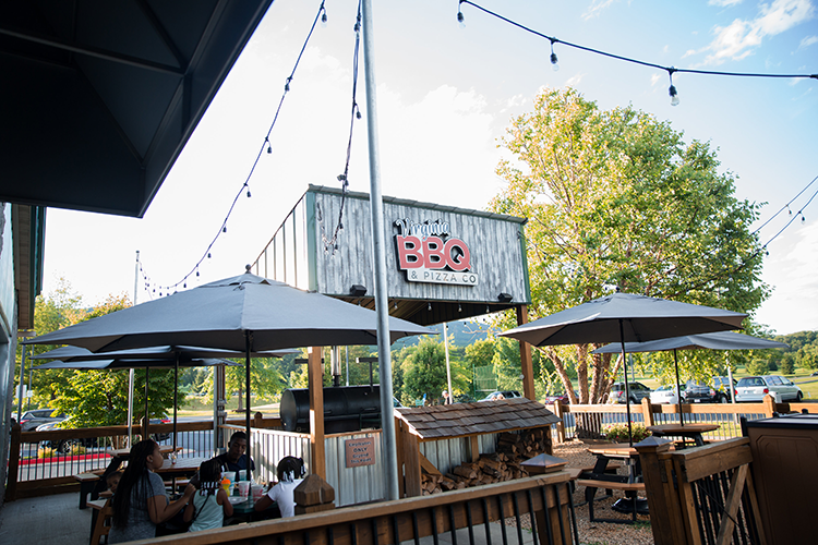 Outdoor shot of Virginia BBQ and Pizza Co restaurant with a Black family eating on the patio