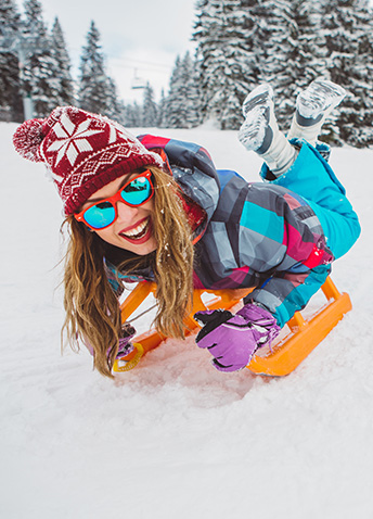 Woman on sled smiling with snowy background